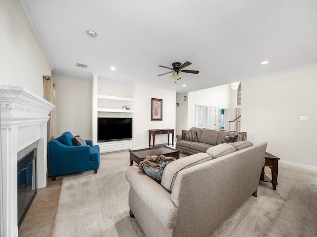 carpeted living room with ceiling fan, crown molding, a textured ceiling, and built in shelves