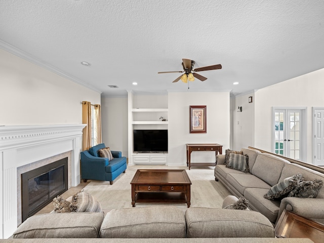 living room with ceiling fan, a textured ceiling, ornamental molding, built in shelves, and french doors