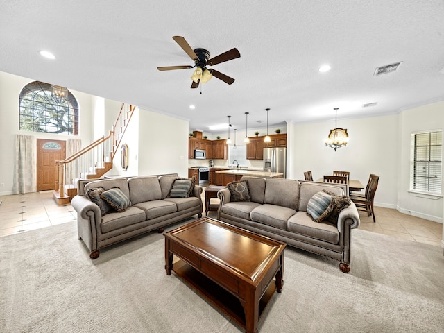 tiled living room featuring ornamental molding, sink, a textured ceiling, and ceiling fan with notable chandelier