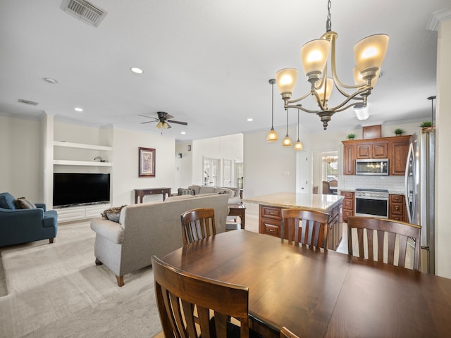 dining area with crown molding, light colored carpet, ceiling fan with notable chandelier, and built in shelves