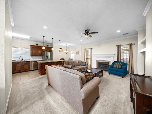 carpeted living room with ceiling fan, a textured ceiling, ornamental molding, a tile fireplace, and sink