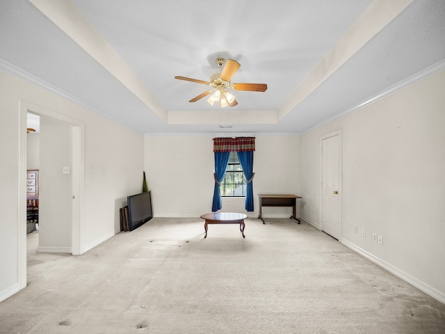 spare room with crown molding, light colored carpet, a tray ceiling, and ceiling fan