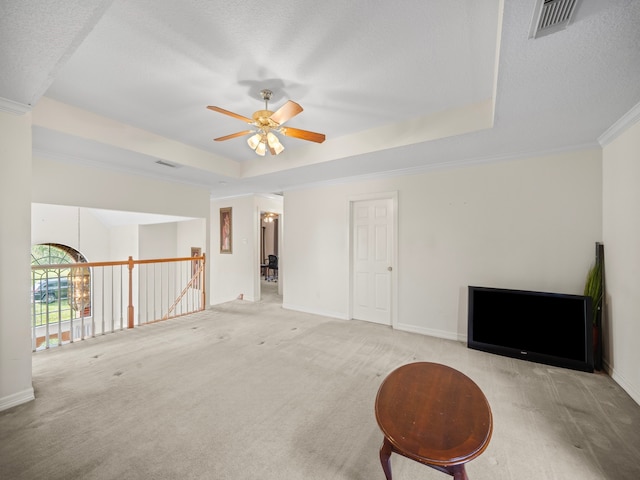 interior space with crown molding, light colored carpet, a raised ceiling, and ceiling fan