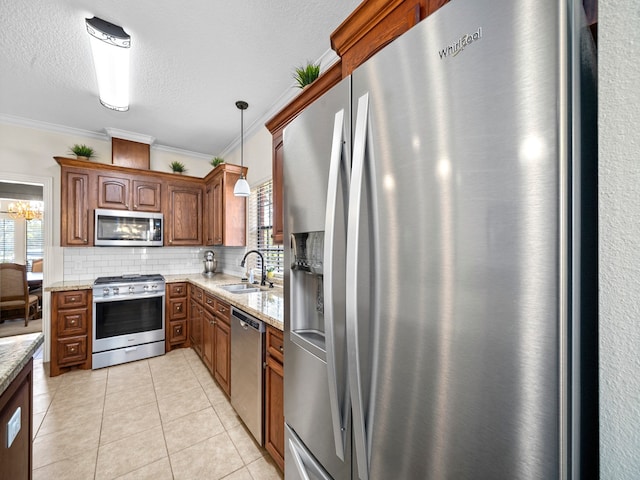 kitchen with appliances with stainless steel finishes, sink, decorative light fixtures, and ornamental molding