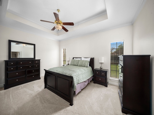 bedroom featuring ornamental molding, a tray ceiling, light colored carpet, and ceiling fan