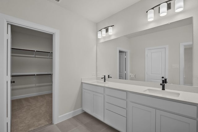 bathroom featuring double vanity, baseboards, tile patterned floors, and a sink