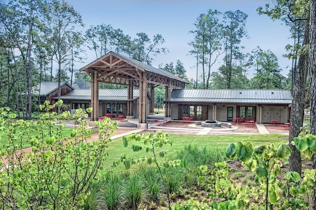 back of property featuring a patio area, an outdoor fire pit, and a standing seam roof