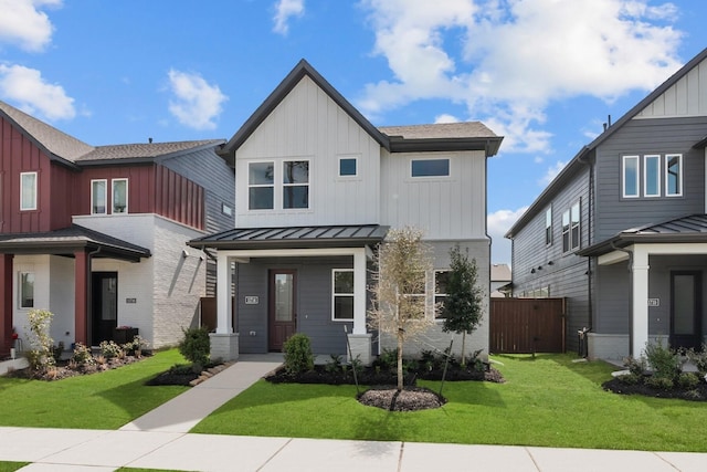 view of front of home featuring metal roof, board and batten siding, a front yard, and a standing seam roof