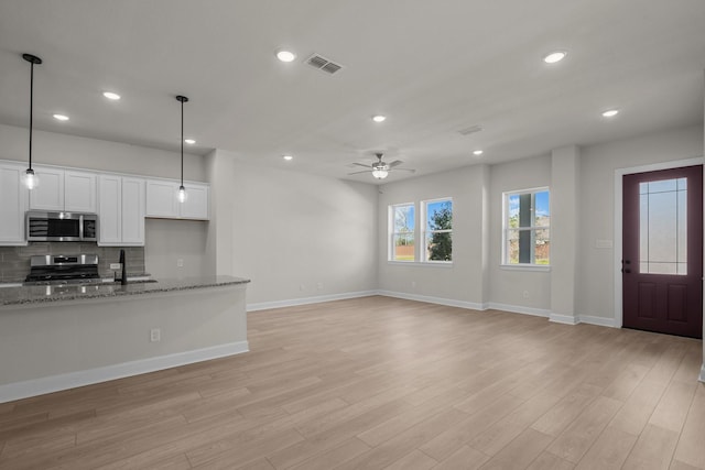 kitchen featuring visible vents, white cabinets, light wood-style floors, appliances with stainless steel finishes, and tasteful backsplash