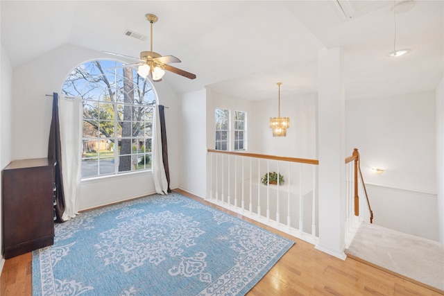 living area featuring lofted ceiling, wood-type flooring, and ceiling fan with notable chandelier