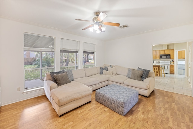 living room featuring ornamental molding, light hardwood / wood-style flooring, ceiling fan, and washer / clothes dryer