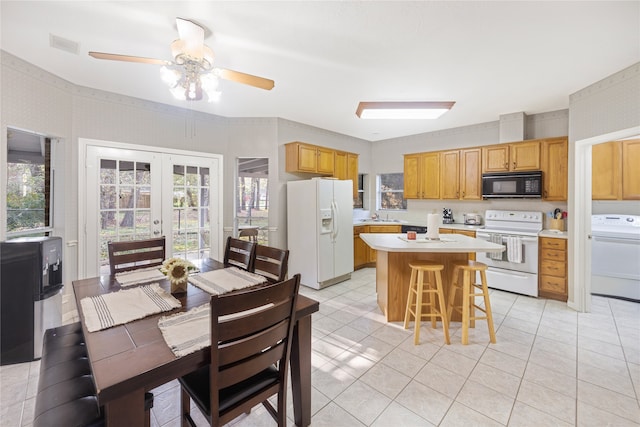 kitchen featuring white appliances, washer / clothes dryer, plenty of natural light, and a kitchen breakfast bar