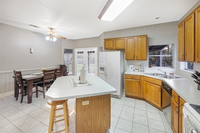 kitchen featuring ceiling fan, a kitchen bar, sink, a center island, and white appliances