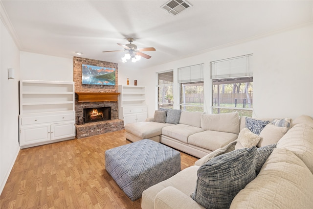 living room featuring light hardwood / wood-style floors, ornamental molding, ceiling fan, and a brick fireplace