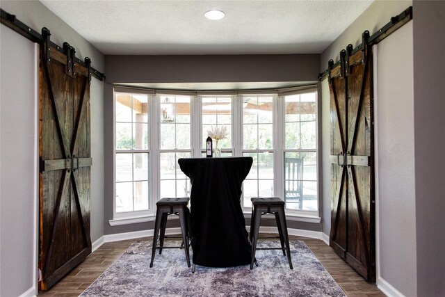 dining space featuring a barn door, hardwood / wood-style flooring, and a textured ceiling