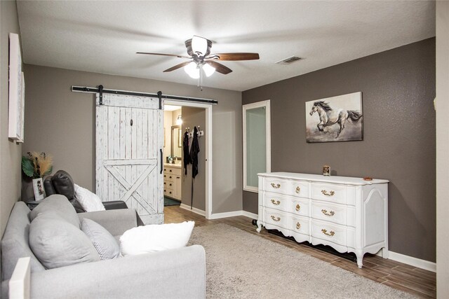 sitting room with light hardwood / wood-style flooring, a barn door, and ceiling fan