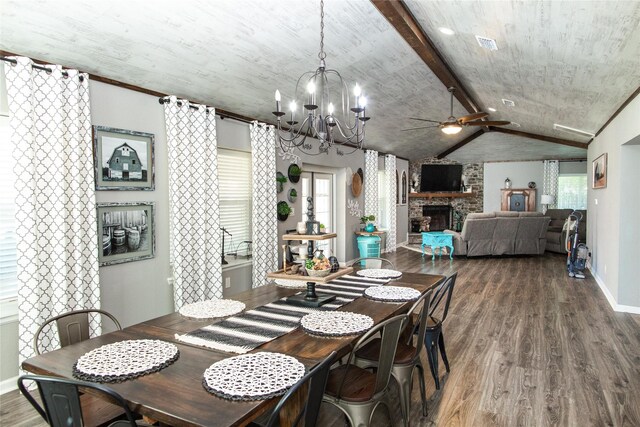 dining room with a stone fireplace, a wealth of natural light, ceiling fan with notable chandelier, and hardwood / wood-style floors