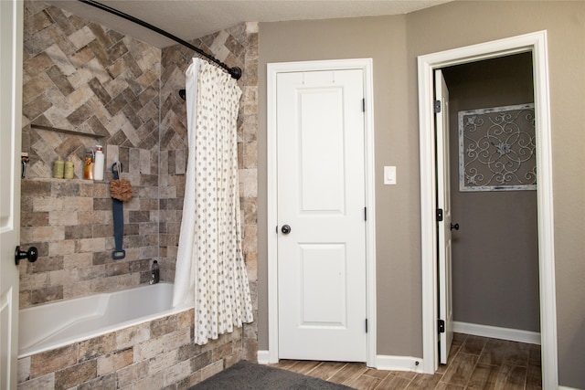 bathroom featuring a textured ceiling, wood-type flooring, and shower / bathtub combination with curtain