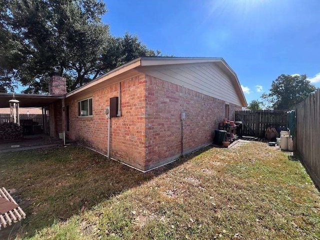 view of side of home with a patio and a lawn