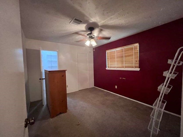 unfurnished bedroom with a textured ceiling, carpet flooring, and ceiling fan