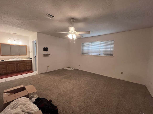 unfurnished bedroom with ensuite bathroom, sink, a textured ceiling, light carpet, and ceiling fan