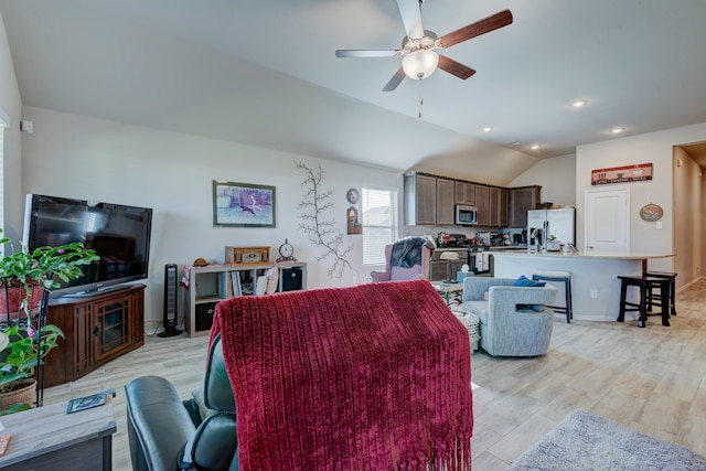 living room with ceiling fan, vaulted ceiling, and light wood-type flooring