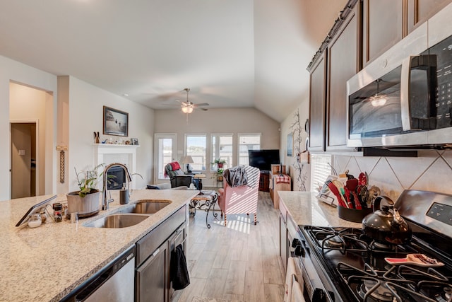 kitchen featuring light stone countertops, appliances with stainless steel finishes, sink, light wood-type flooring, and dark brown cabinets