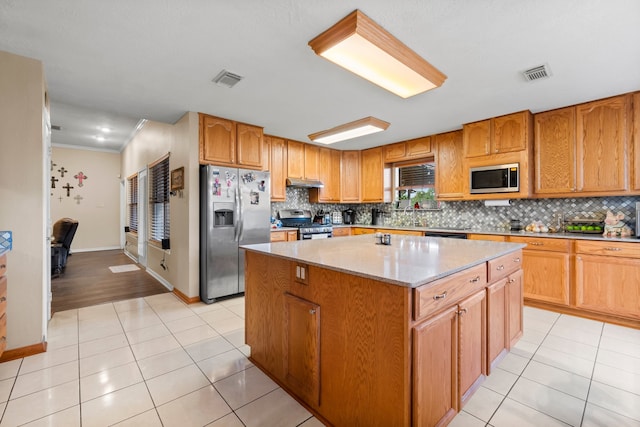 kitchen featuring light tile patterned floors, stainless steel appliances, a center island, and crown molding