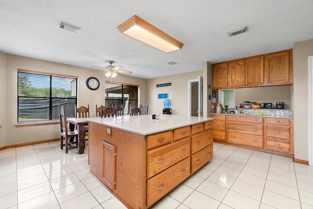 kitchen with light tile patterned flooring, a textured ceiling, a center island, and ceiling fan