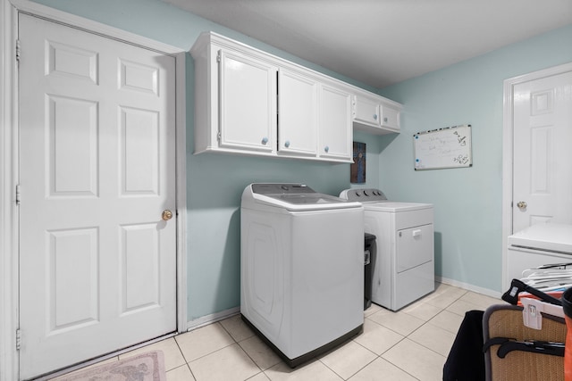 laundry area featuring light tile patterned floors, cabinets, and washing machine and clothes dryer