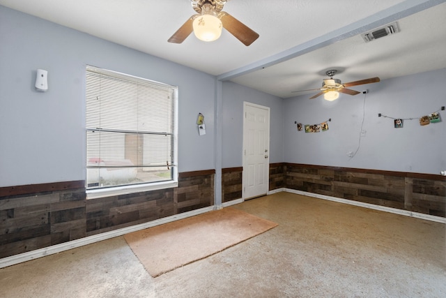 unfurnished room with wood walls and ceiling fan