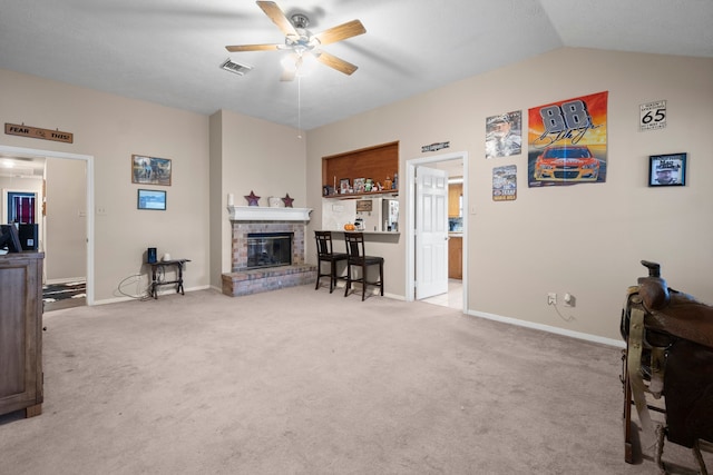 living room with a brick fireplace, ceiling fan, light colored carpet, and vaulted ceiling