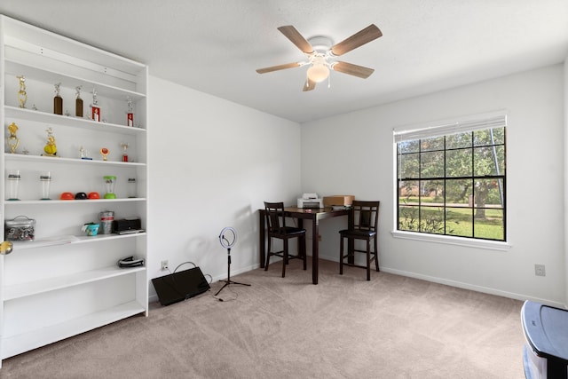 carpeted home office featuring ceiling fan