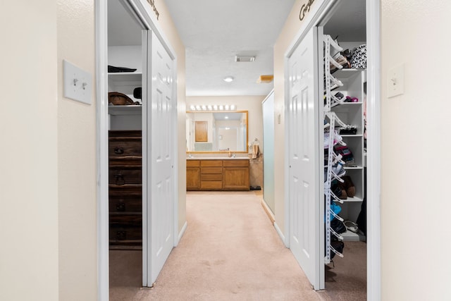 hall with sink and light colored carpet