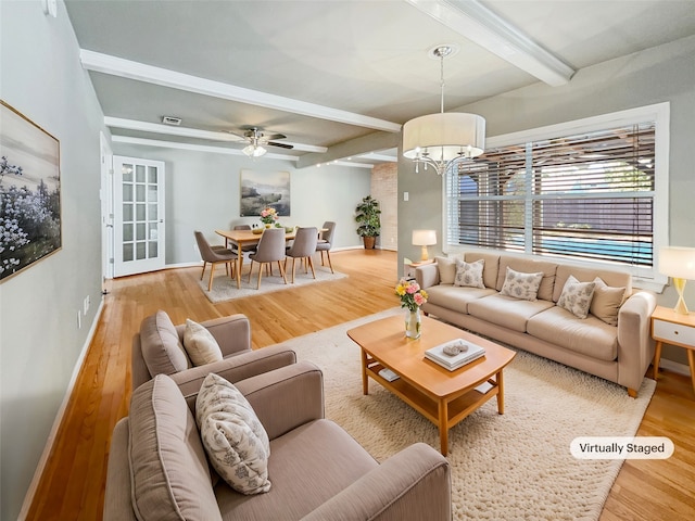 living room featuring beam ceiling, wood-type flooring, and ceiling fan with notable chandelier