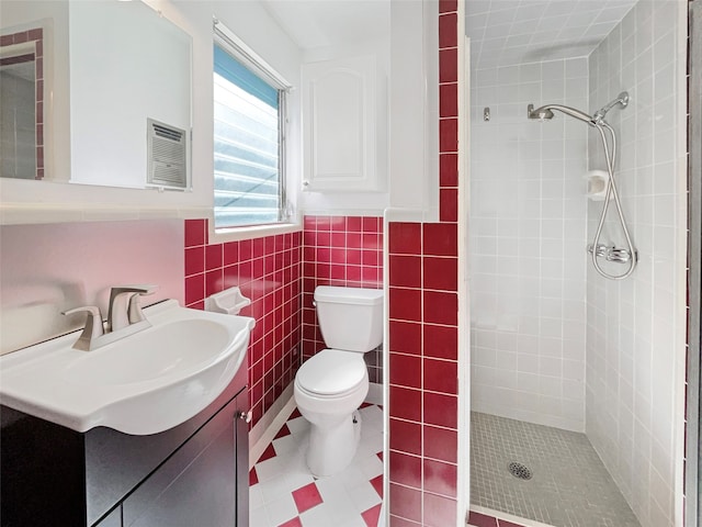 bathroom featuring vanity, toilet, tile walls, and tiled shower