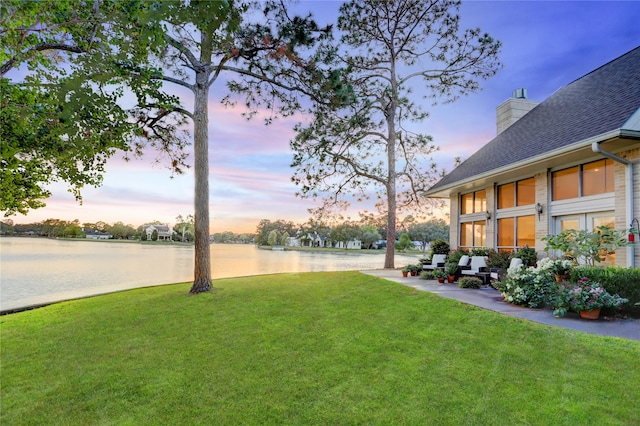 yard at dusk featuring a water view