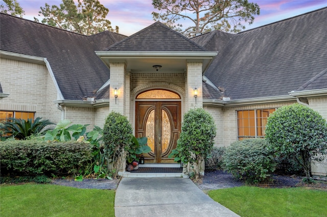 exterior entry at dusk featuring a lawn