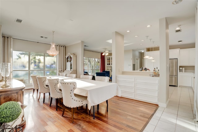 dining room with light wood-type flooring and ceiling fan with notable chandelier