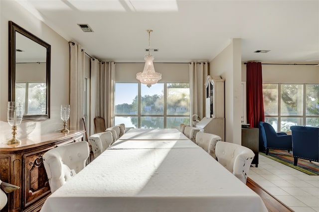 dining space with a wealth of natural light, crown molding, an inviting chandelier, and light tile patterned floors