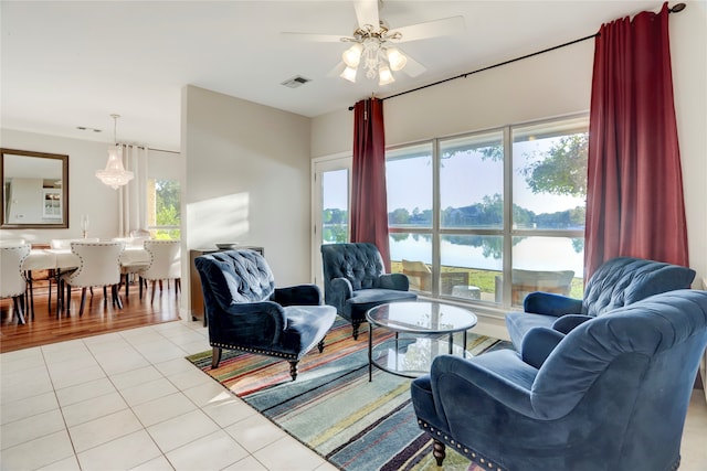 living room featuring a water view, ceiling fan, and light tile patterned floors