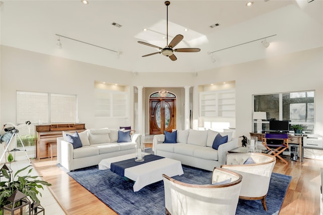 living room with light wood-type flooring, built in features, rail lighting, ornate columns, and ceiling fan