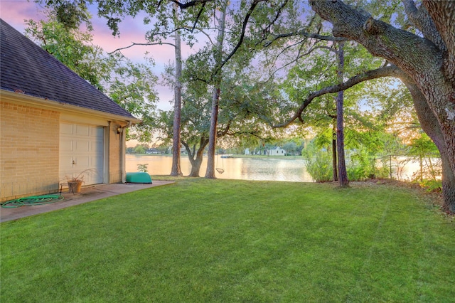 yard at dusk featuring a water view