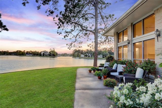 yard at dusk featuring a water view