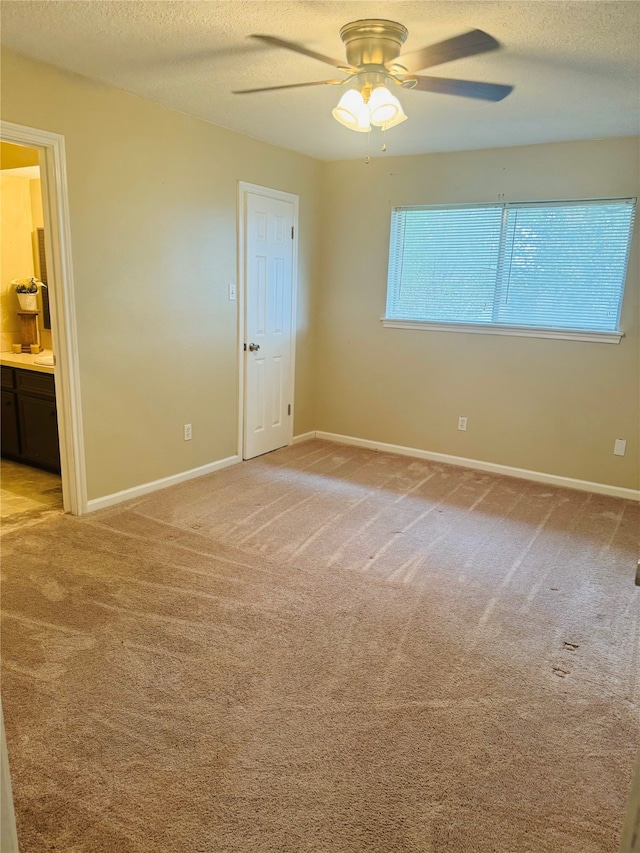 unfurnished bedroom with ceiling fan, ensuite bathroom, light colored carpet, and a textured ceiling