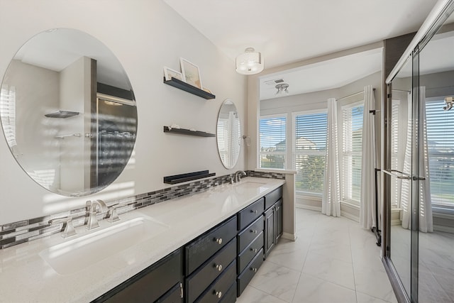 bathroom with vanity, a shower with shower door, and tasteful backsplash