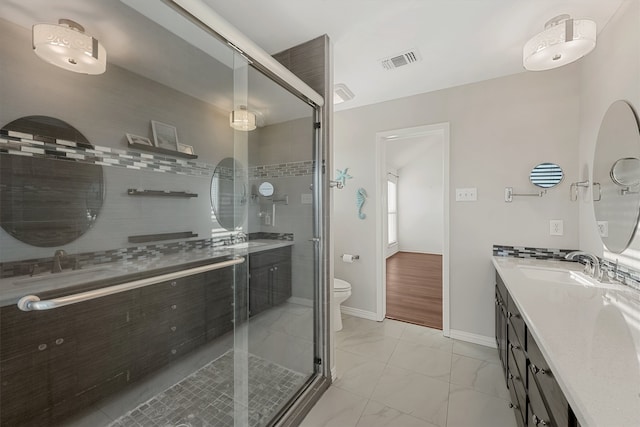 bathroom featuring vanity, toilet, and a shower with door