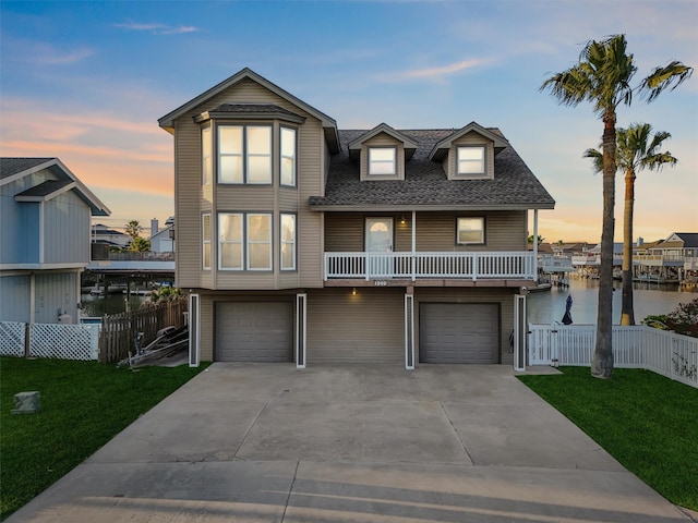 view of front of property featuring a garage, a water view, and a lawn