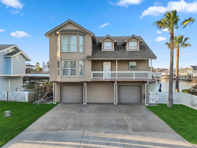 view of front of property with a front yard, a garage, and a water view