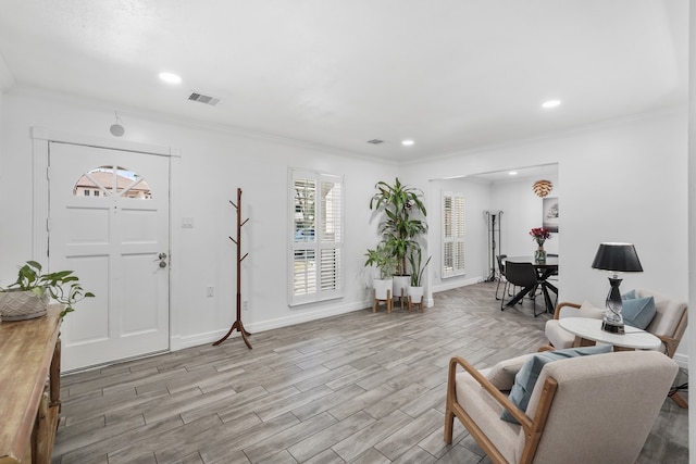 foyer with crown molding and light hardwood / wood-style flooring